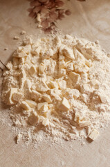 flour and butter in large pieces in the process of making cookies on the table