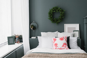 Stylish Christmas bedroom. Pillows on the bed and a wreath on the wall