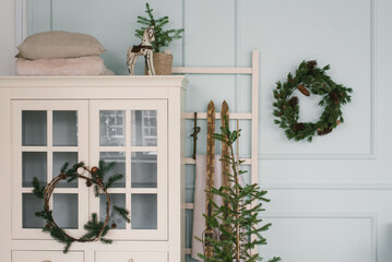 Christmas decor in the interior of the room. Christmas tree, wreath and white wardrobe in blue and white tones