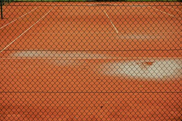 Tennisplatz hinter Gitterzaun bei Regen im Herbst