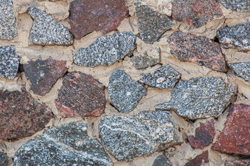 Texture of torn stones of different sizes and shapes. Background wall of rubble gray and red