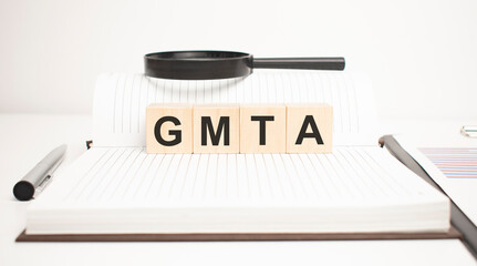 gmta word concept. wooden cubes, notepad, pen and business charts.