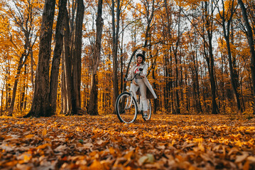 Young woman riding on retro bicycle in yellow autumn park. Amazing scene of trendy girl on nature...