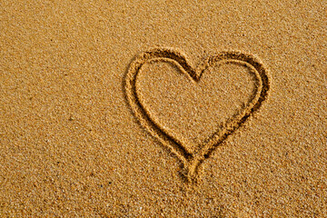 Fototapeta na wymiar Heart sign written on sand in evening sunlight