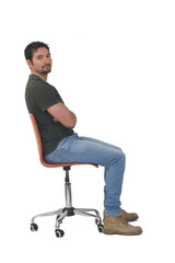 side view of a full portrait of man sitting on chair looking at camera and arms crossed on whige background
