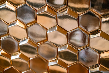 gold volumetric honeycomb elements forming an uneven shiny surface, blurred image