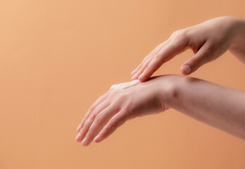Fototapeta premium Young female hands applying cream or lotion