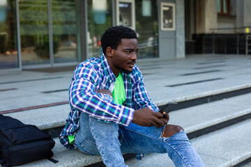 The pensive student sits in front of the university building