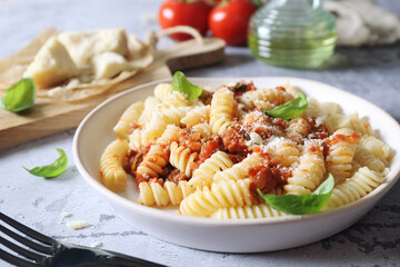 Fusilli pasta with bolognese sauce and grated parmesan cheese, olive oil and basil