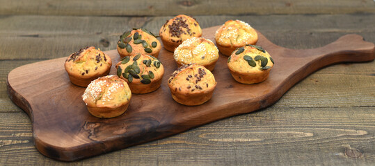 Salty and tasty muffins, baked and decorated with seeds toper placed on the wooden table, bakery ideas 