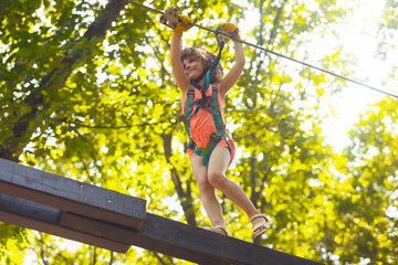The concentrated girl carefully overcomes obstacles in the rope park