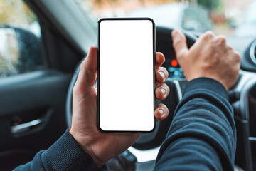 Car driver holding mobile smart phone over steering wheel, blank white screen