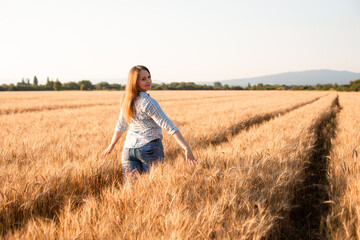 Naklejka na ściany i meble Charming woman enjoying moment, walking in grain field