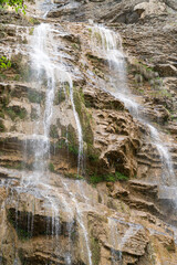 Fototapeta na wymiar waterfall flowing down from a cliff close-up. vertical photo