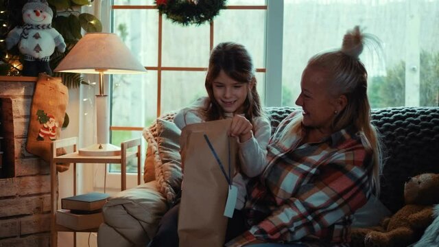 Mother surprises her little daughter by giving a Christmas present. Slow motion