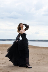 Happy young girl in a straw hat and in a black dress on the bank of the river. Thunder Sky