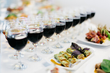 red wine and light signature snacks on a white tablecloth at a festive stand