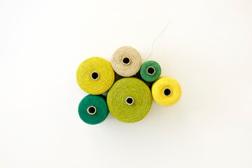 Arrangement of threads in shades of green, white background, flat lay. Equipment to creative project concept, DIY, hobby, design works. Colourful cord spool from above, circle shape set of colors.