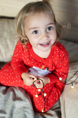 Christmas morning. Toddler girl red pajamas having fun in bed