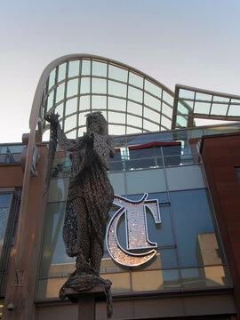 the statue of minerva in front of the sign and logo above the entrance to the trinity shopping centre in leeds