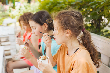 The kids are eating ice cream in the outdoor cafe - 467793082