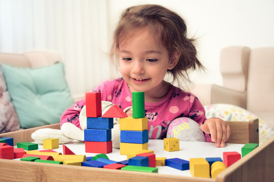 girl child doing play activity with wooden blocks on her desk at home