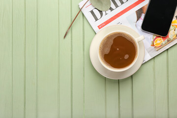 Cup of coffee and newspaper on green wooden background