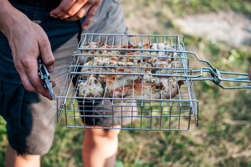mens puts meat skewers in a grid summer