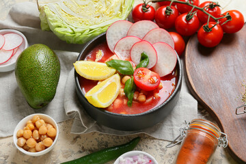 Bowl with delicious homemade pozole soup and ingredients on color background