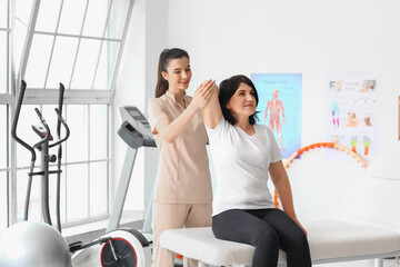 Mature woman having therapy with physiotherapist in rehabilitation center