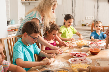 the teacher is learning children to cook pizza