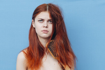 pretty woman combing naughty hair blue background