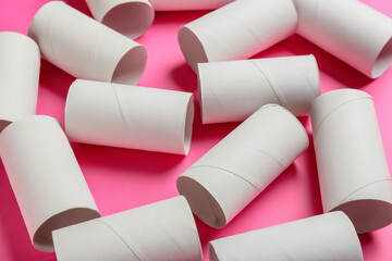 Toilet paper cardboard tubes on pink background, closeup