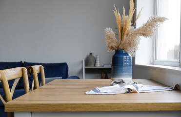 Vase with bouquet of beautiful dried flowers on wooden table in room