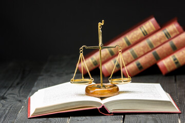 Law concept - Open law book with a wooden judges gavel on table in a courtroom or law enforcement...