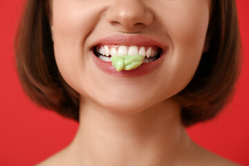 Young woman with chewing gum on color background, closeup
