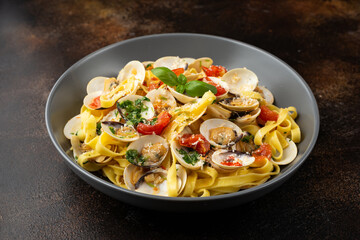 White shell clams in Garlic and parsley white wine sauce tagliatelle pasta served with cherry tomatoes and parmesan cheese