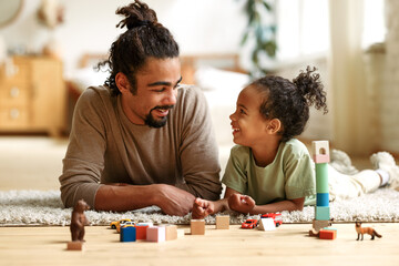 Happy african american family father and child son laughing while playing toys together at home - Powered by Adobe