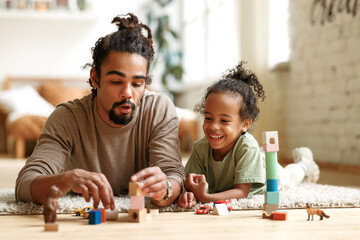 Happy african american family father and child son laughing while playing toys together at home - 467797672