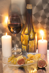 Still life of romantic dinner with candles, wineglasses, decorated bottle and cheese and fruits