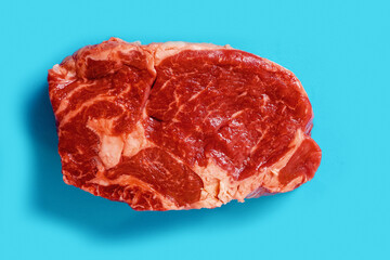 Fresh juicy rib eye steak on blue surface. Top quality fresh meat. Butcher craft product and meat industry. Rich red color and marbling. Premium cut.