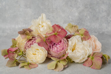 Closeup flower arrangement of roses and hydrangeas on a gray background.