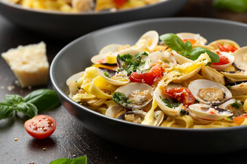 White shell clams in Garlic and parsley white wine sauce tagliatelle pasta served with cherry tomatoes and parmesan cheese
