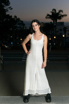 Confident High School Senior Girl Stands With Hand On Hip With Sunset Over Ventura With Evening Lamps