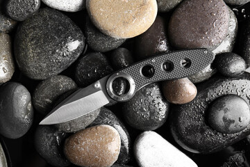 Folding pocket knife with rubberized handle on rocks background