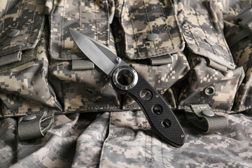 Folding pocket knife with rubberized handle lying on army's clothing