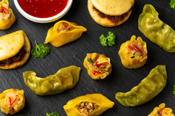 Dim Sum dumplings and Bao buns on rustic stone board. Traditional Chinese food