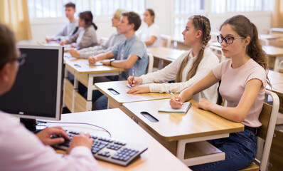 Fototapeta premium Teen students listening lecture of teacher, smart young people studying at college