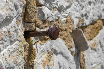 Close up of an old rusty nail driven into a stone wall