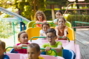 Photo sur Plexiglas Parc dattractions Les enfants heureux sur des montagnes russes dans le parc d& 39 attractions